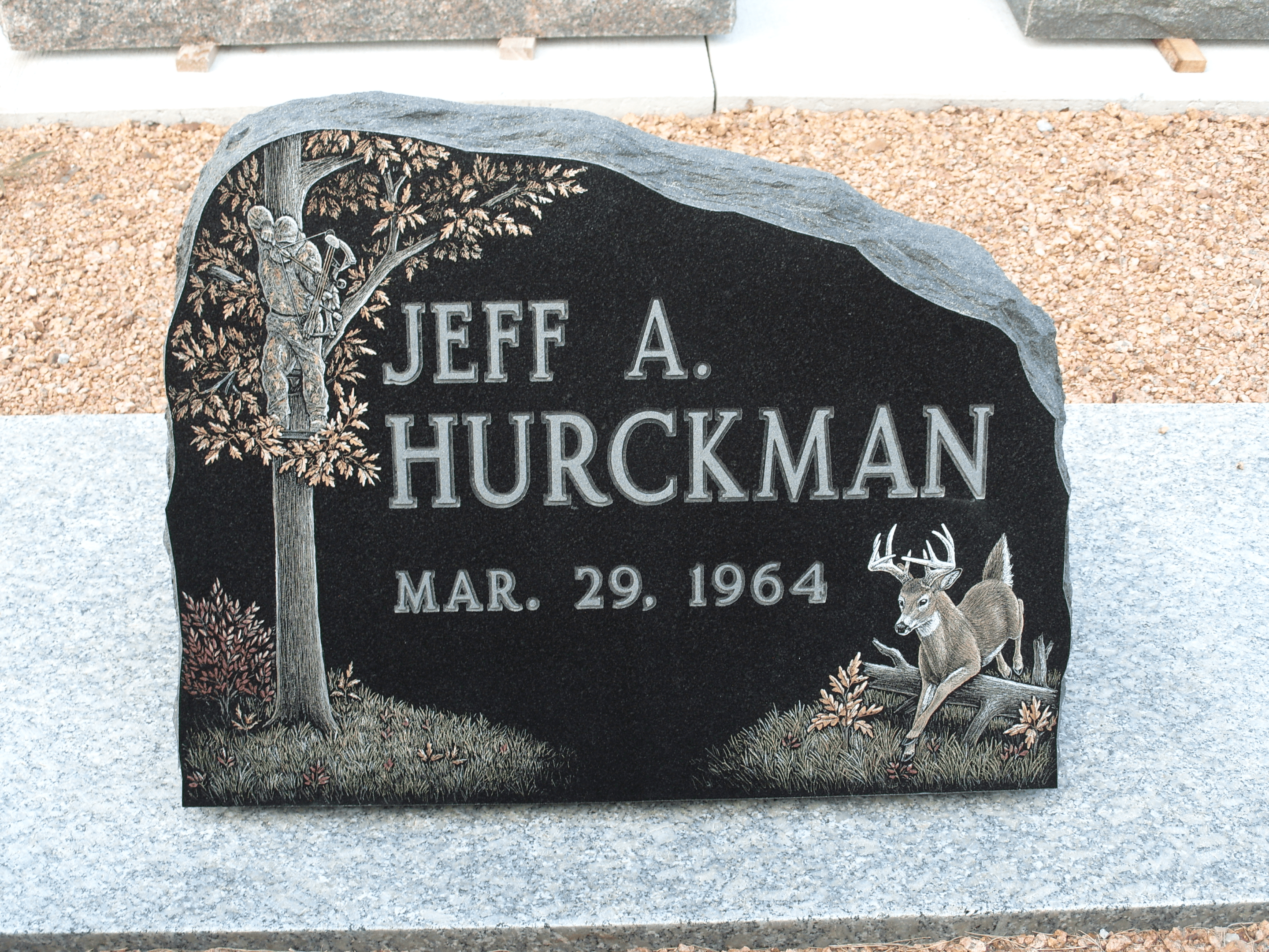 A grave marker with a deer and tree on it.